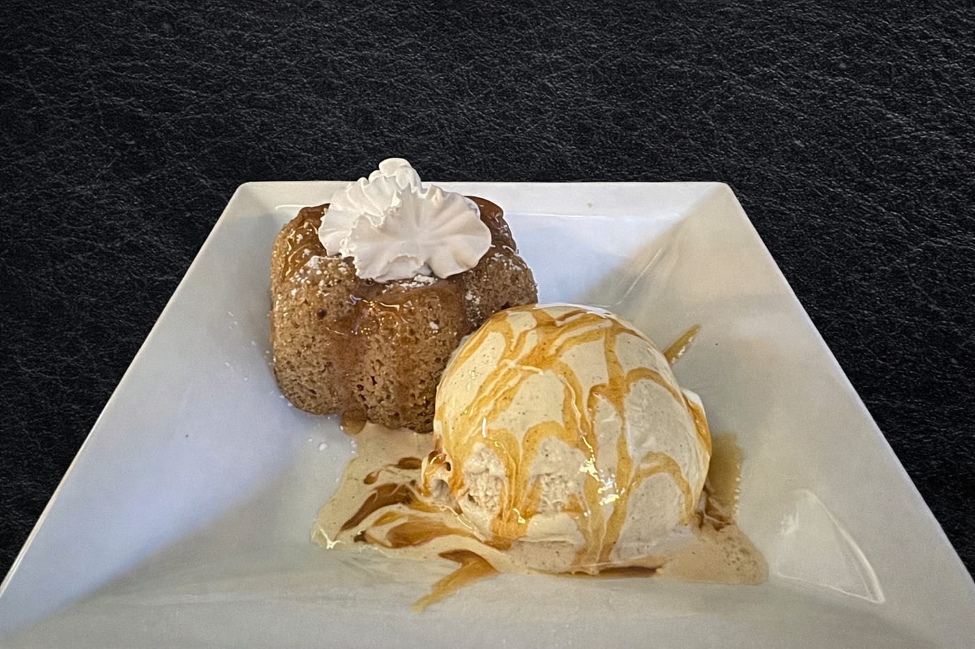 Churro Cake with whipped cream and a scoop of ice cream drizzled with caramel at Oak and Iron