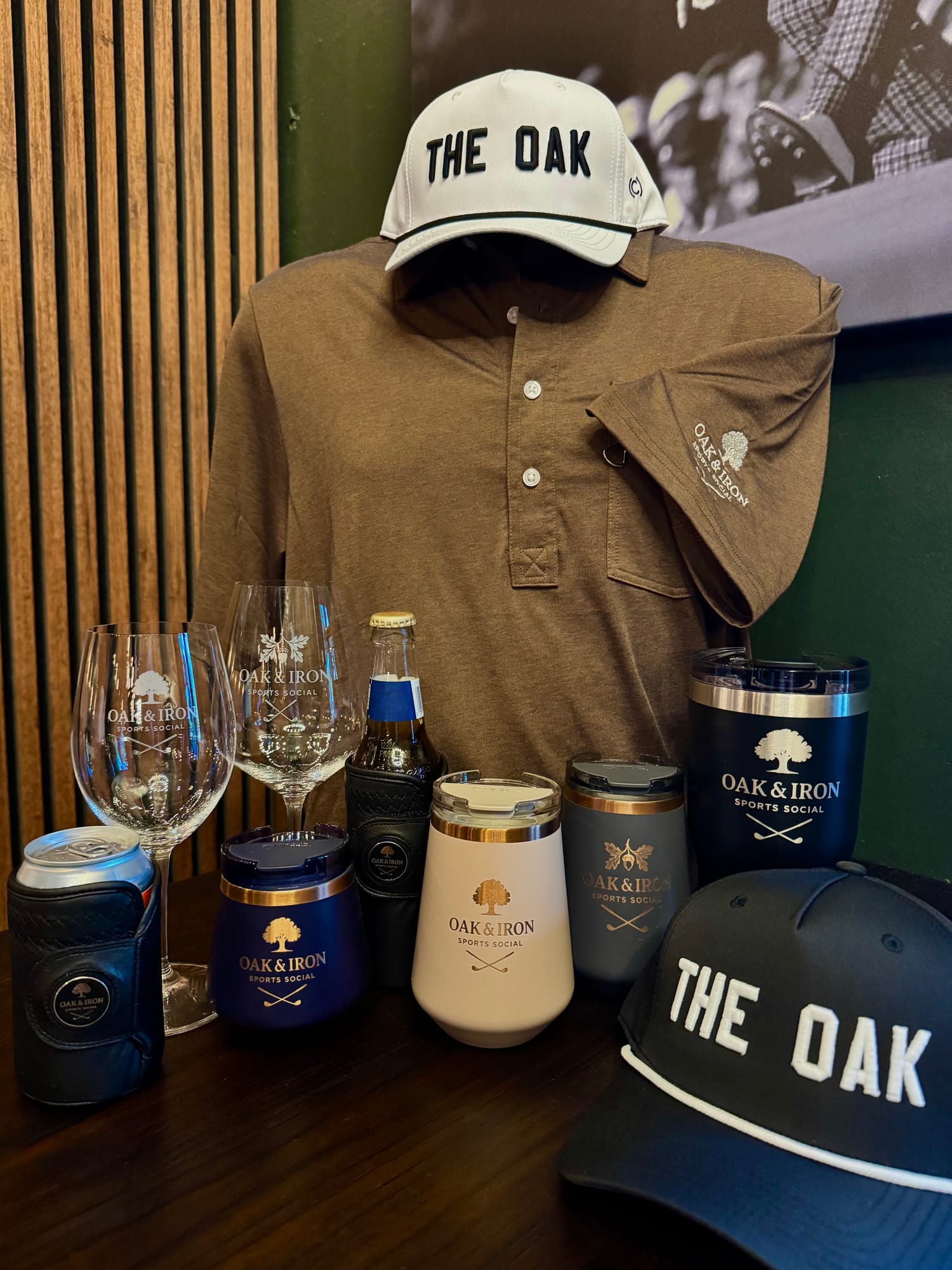 Oak and Iron Sports Social branded merchandise including hats, a polo shirt, glassware and tumblers