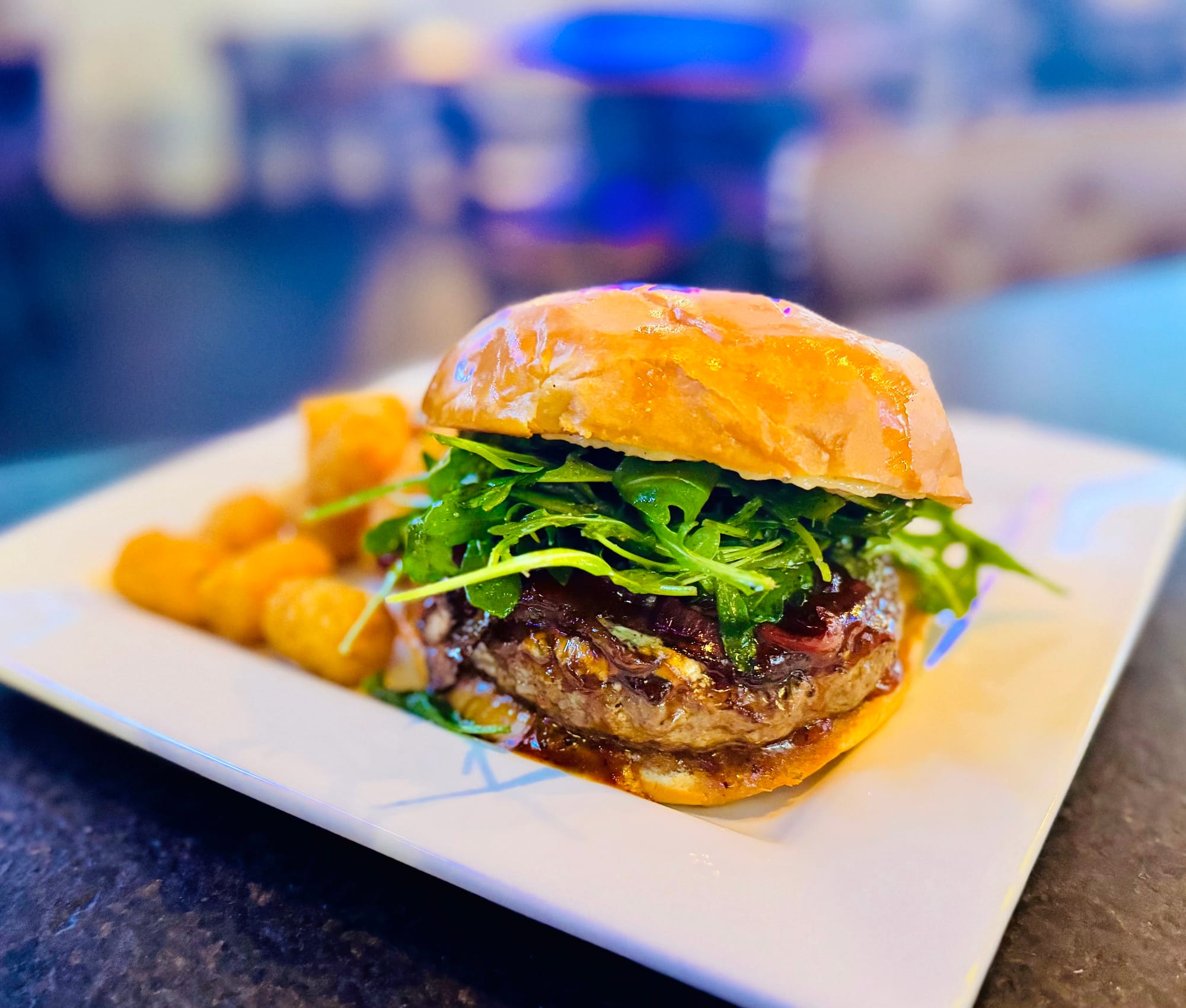 The Exotic Burger with arugula, caramelized onions and tater tots at Oak and Iron