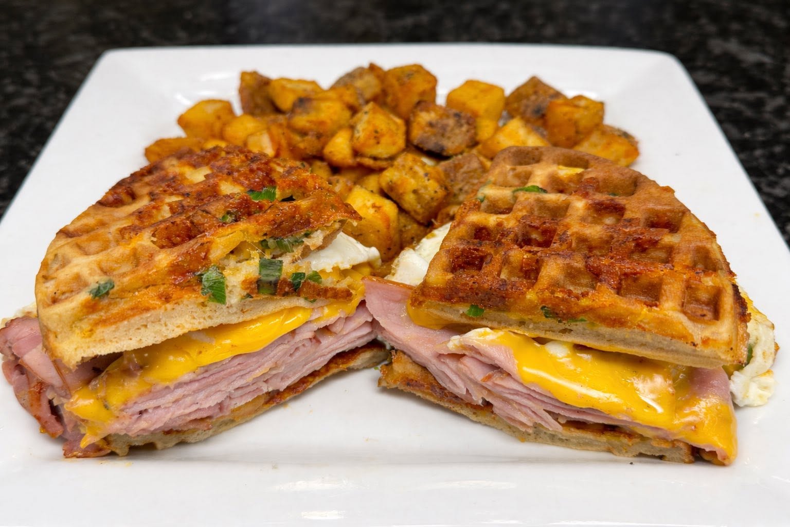 Ham, egg and cheese waffle sandwich with breakfast potatoes served at Oak and Iron